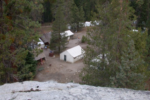 The camp from the granite slope above — tent cabins and the central buildings tucked into the forest clearing.
