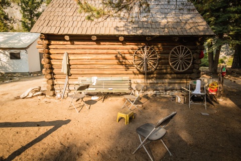Folding chairs gathered outside the log cabin with the wagon wheels.