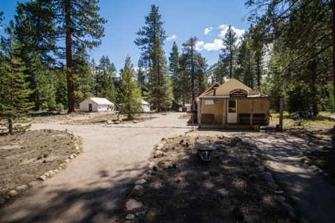 Paths converging at the heart of camp, the office at right and guest tents beyond.