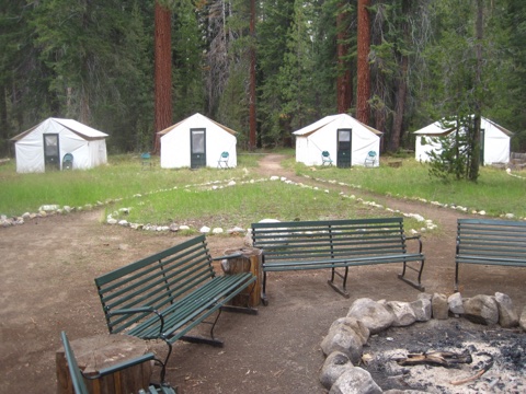 Tent cabins ringing the campfire circle and its green benches.