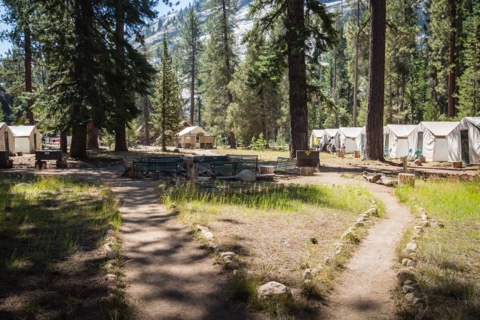 The campfire circle and tent-cabin row from the meadow paths.