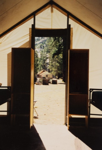 The main building framed by a tent cabin's doorway — an earlier era on film.