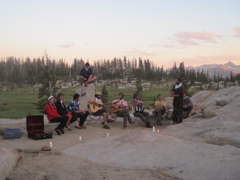 Guitars, an accordion, and candles on the granite — the evening gathering at sunset.