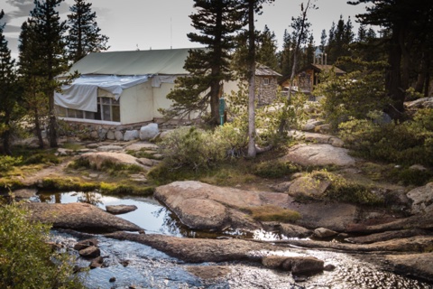 The camp from across the creek, its big canvas-roofed building above the granite slabs.
