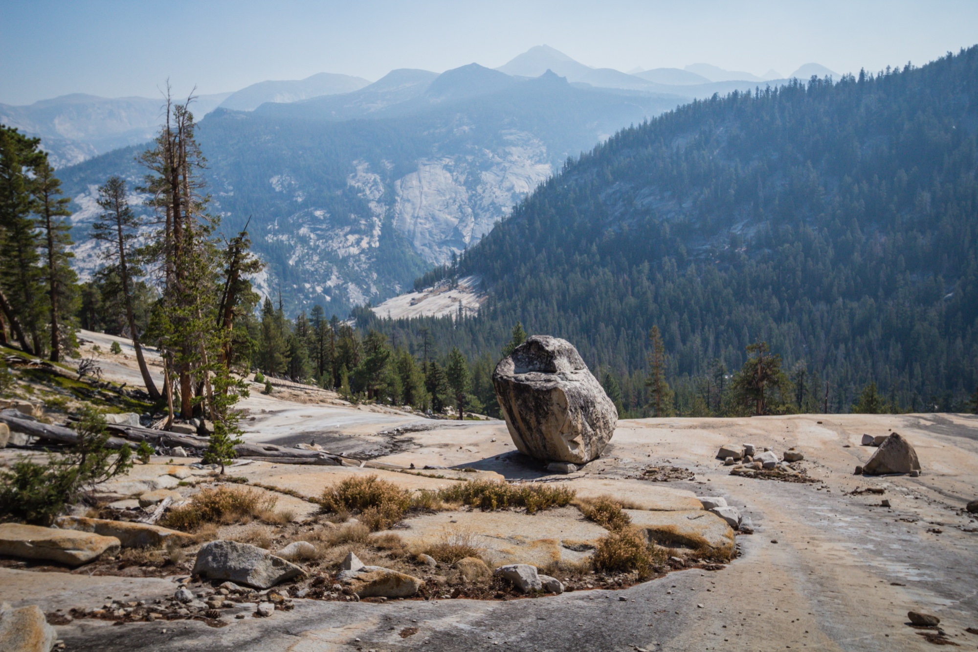 A glacial erratic on granite slabs high above a deep forested canyon