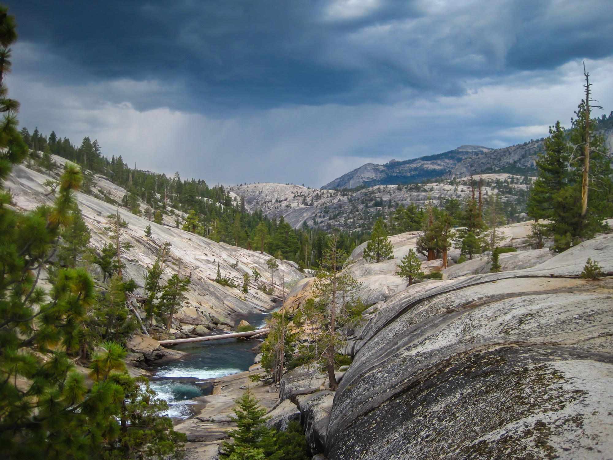 A river bending through a granite canyon under gathering storm clouds